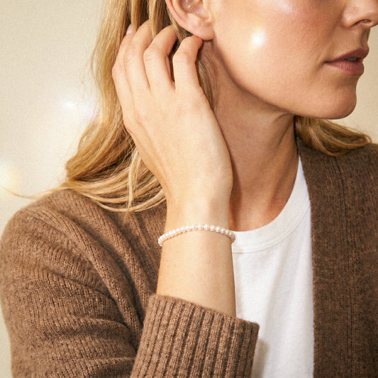 Woman wearing a pearl bracelet with a neutral background
