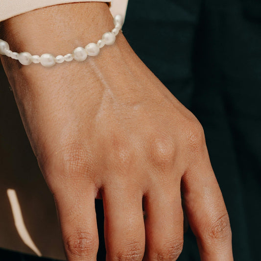 Hand with a pearl bracelet on a dark background