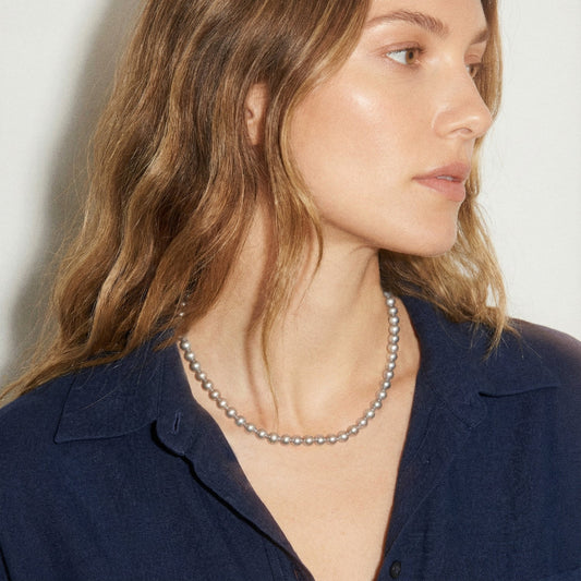Woman wearing a pearl necklace with a plain background