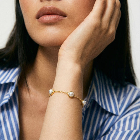 Woman wearing a gold bracelet with pearls, close-up on hand and wrist.