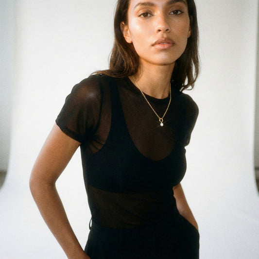 Woman wearing a black sheer top with a white background