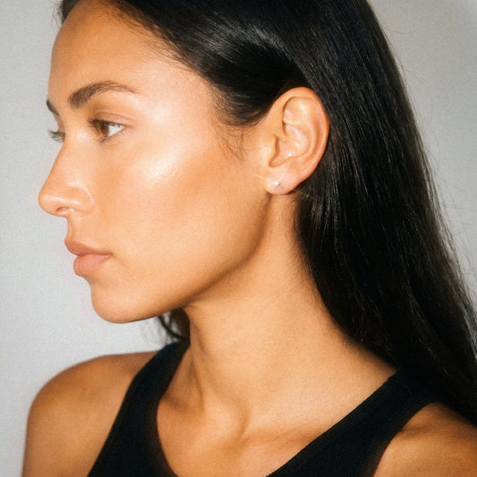 Side profile of a person with long dark hair wearing a black top against a neutral background