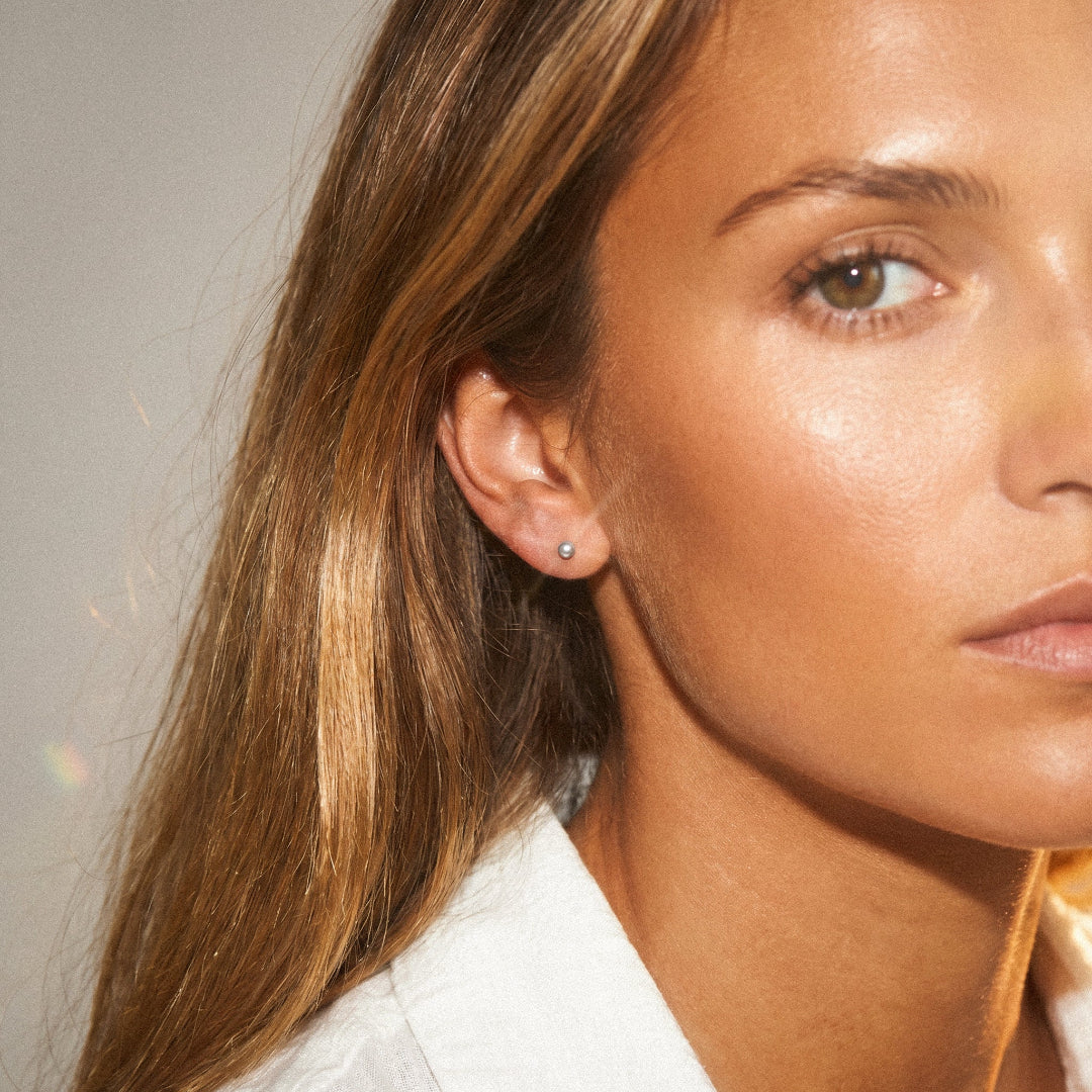 Close-up of a woman wearing earrings with a neutral background
