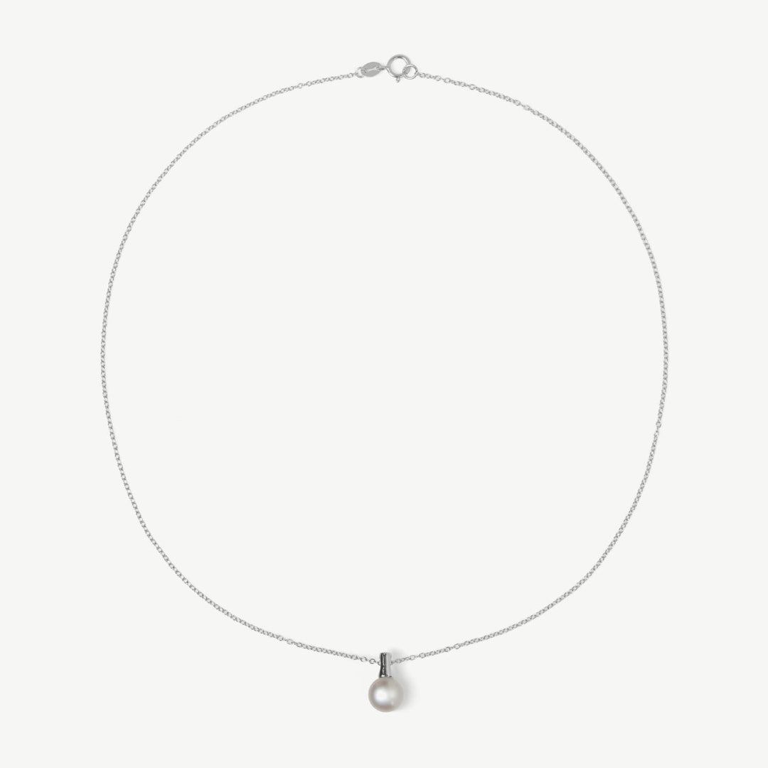 Silver necklace with a small pearl pendant on a light gray background