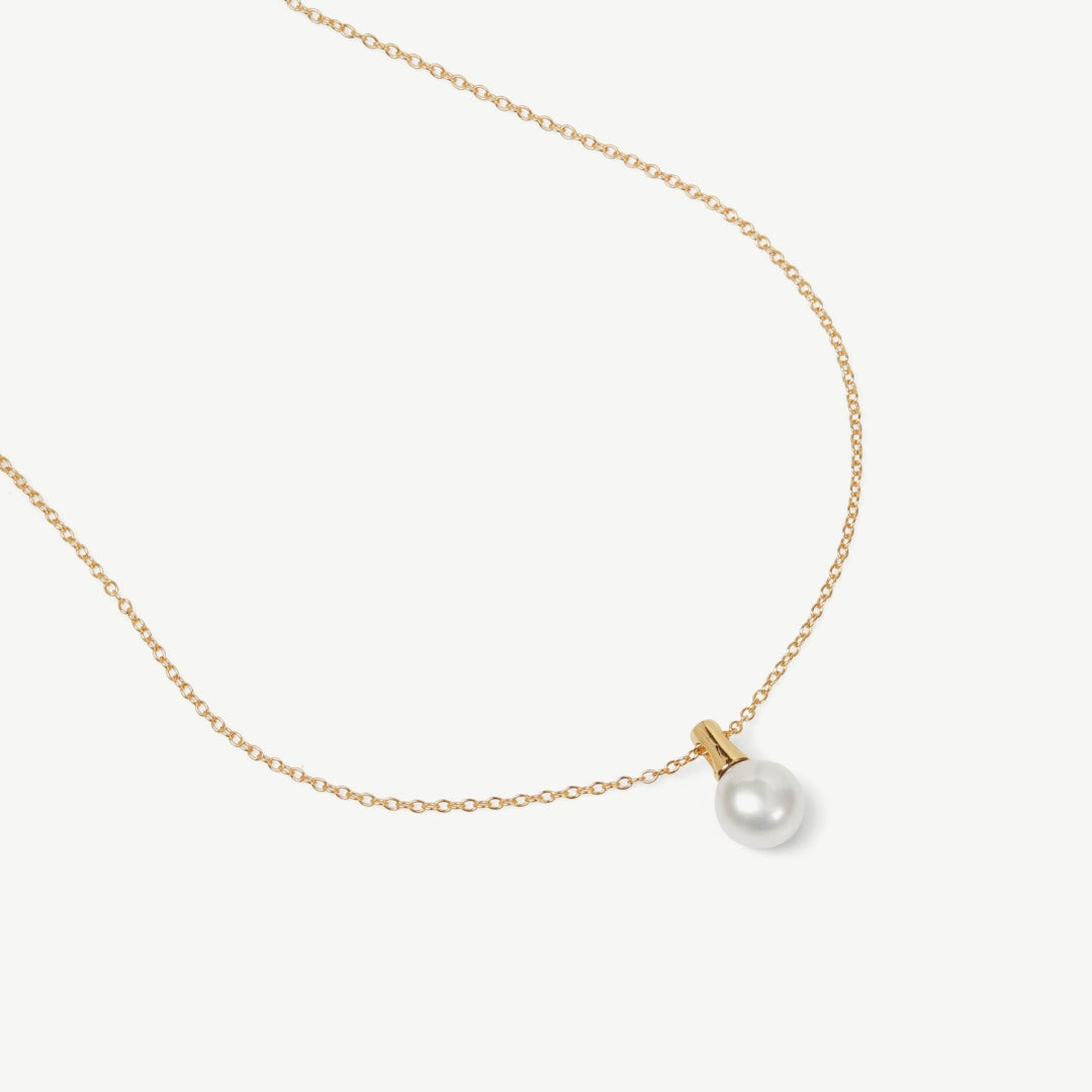 Gold necklace with a single pearl pendant on a white background