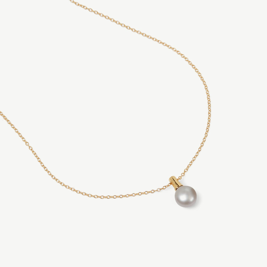 Gold necklace with a single pearl pendant on a white background