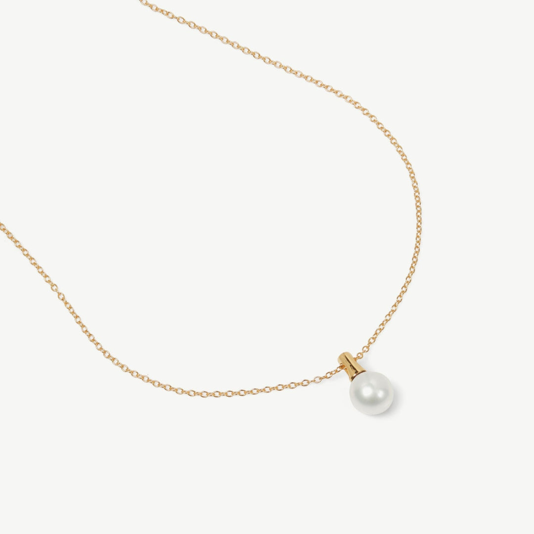Gold necklace with a single pearl pendant on a white background