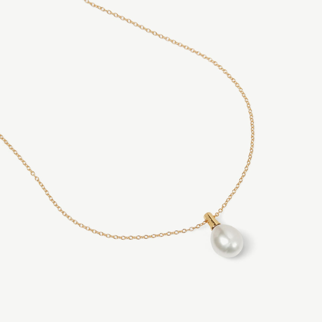 Gold necklace with a single pearl pendant on a white background
