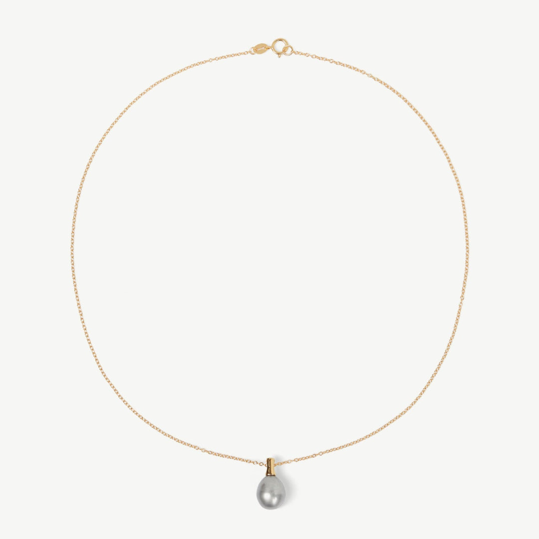 Gold necklace with a single pearl pendant on a white background