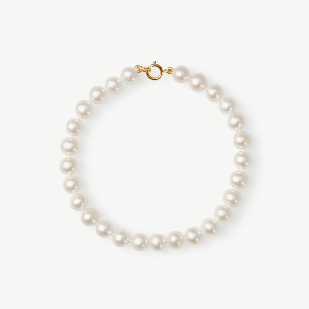 Pearl bracelet with gold clasp on a white background
