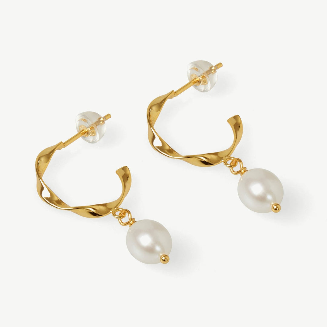 Gold hoop earrings with pearl drops on a white background