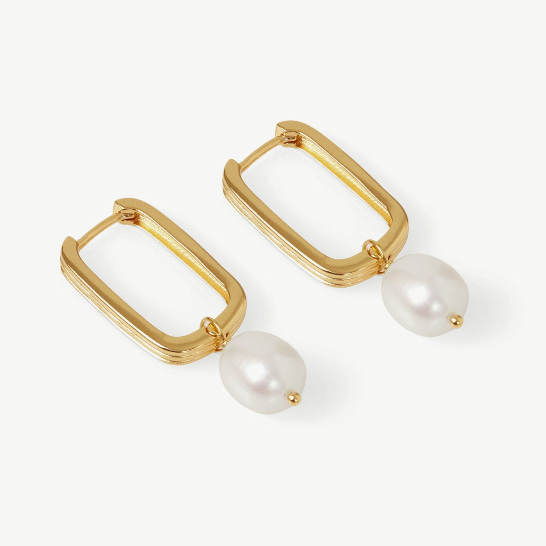 Gold hoop earrings with pearl drops on a white background