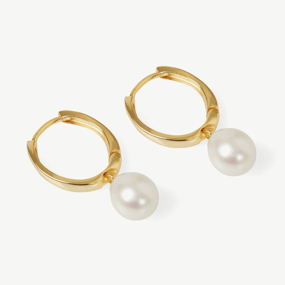 Gold hoop earrings with pearl drops on a white background