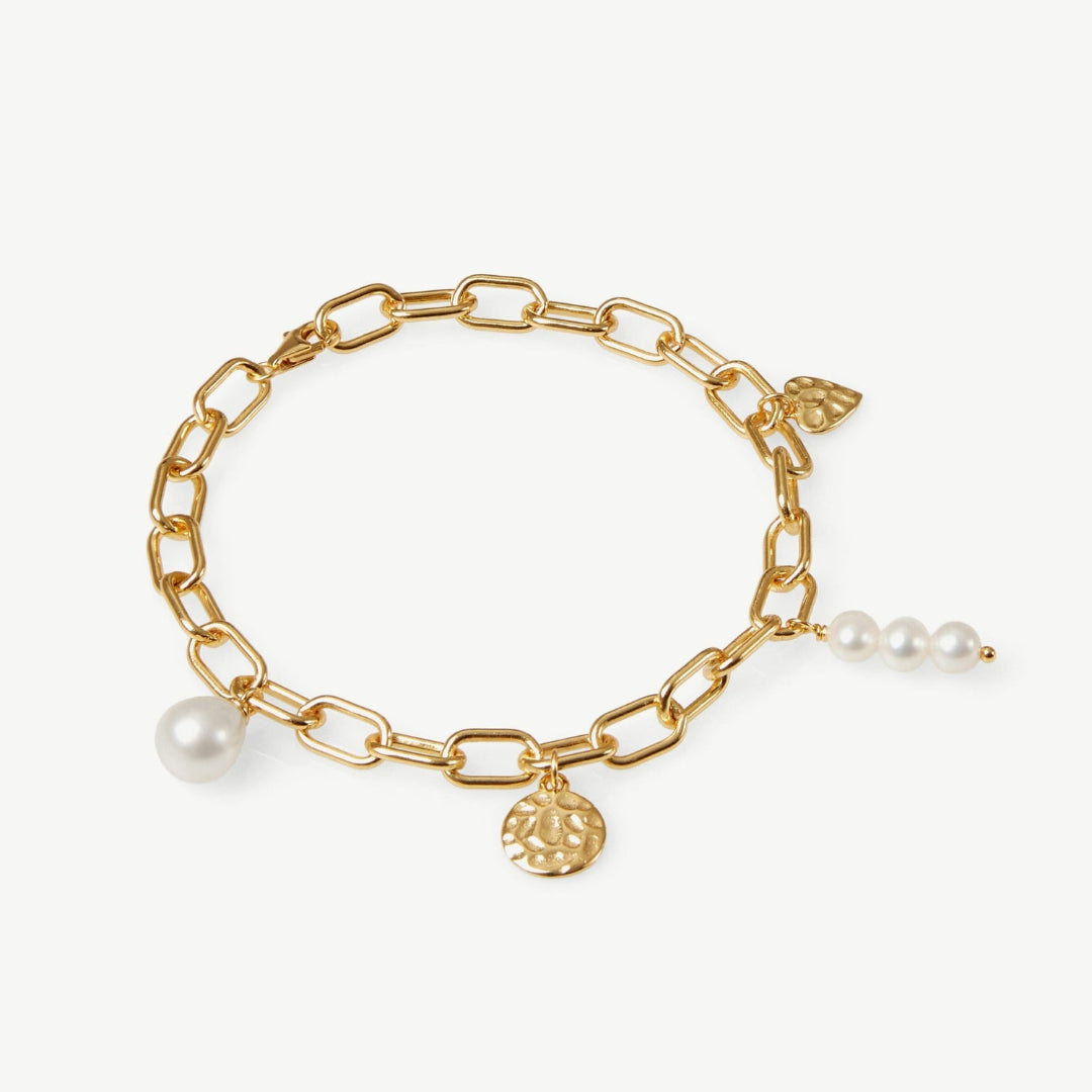Gold chain bracelet with pearls and a round charm on a white background