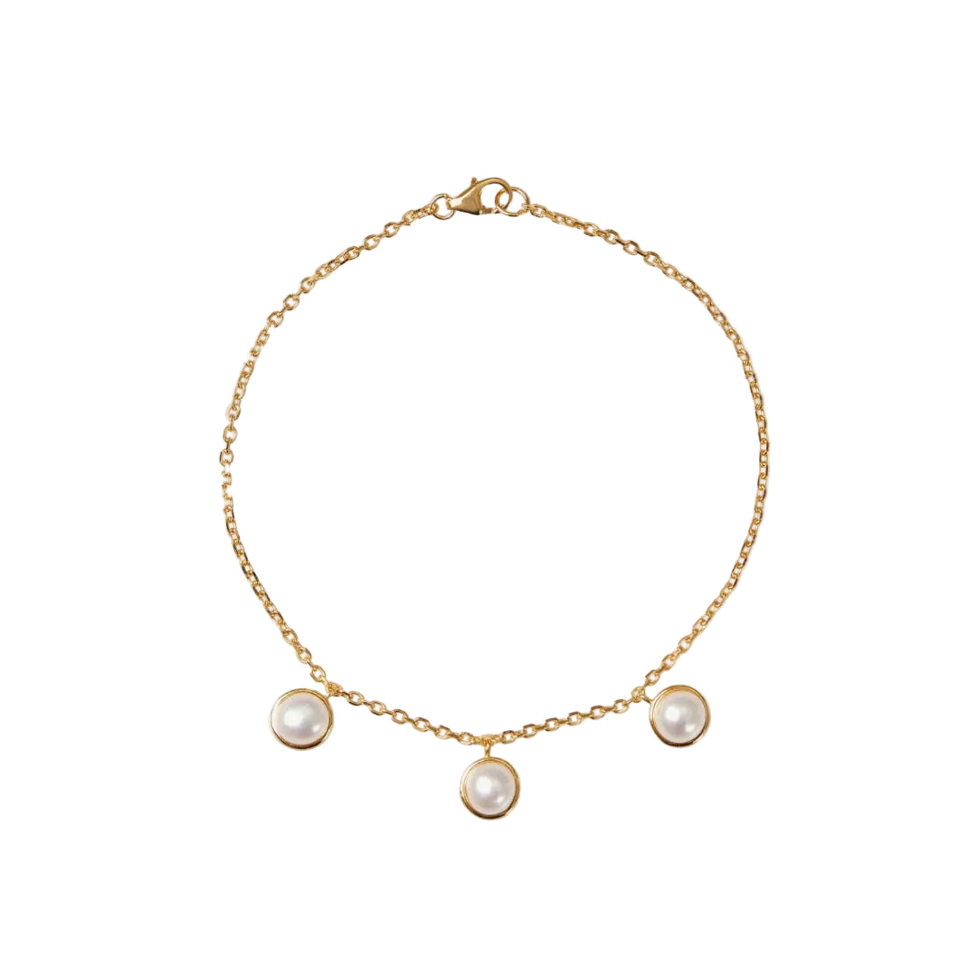 Gold bracelet with three pearl charms on a white background