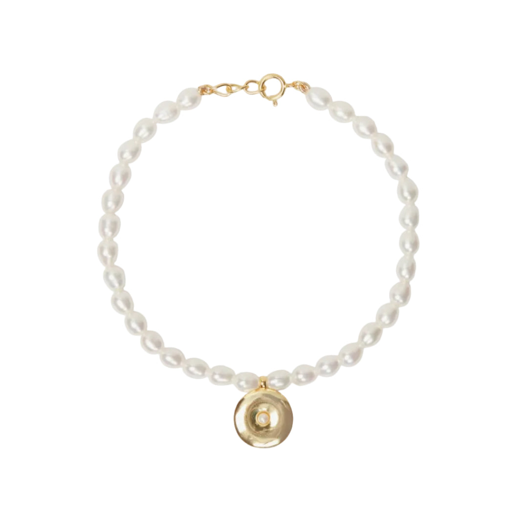 Pearl bracelet with a gold charm on a white background