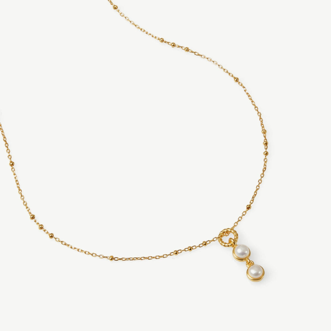 Gold necklace with two pearls on a white background