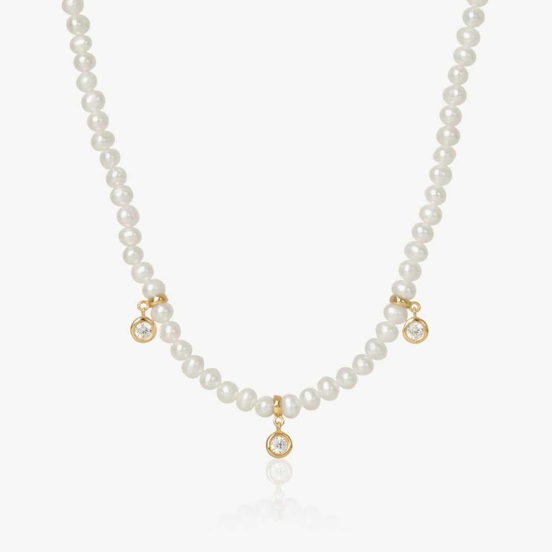 Pearl necklace with gold accents and small diamonds on a white background