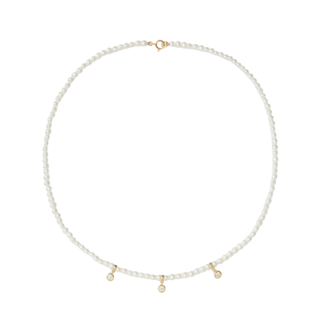 Pearl necklace with gold accents on a light gray background
