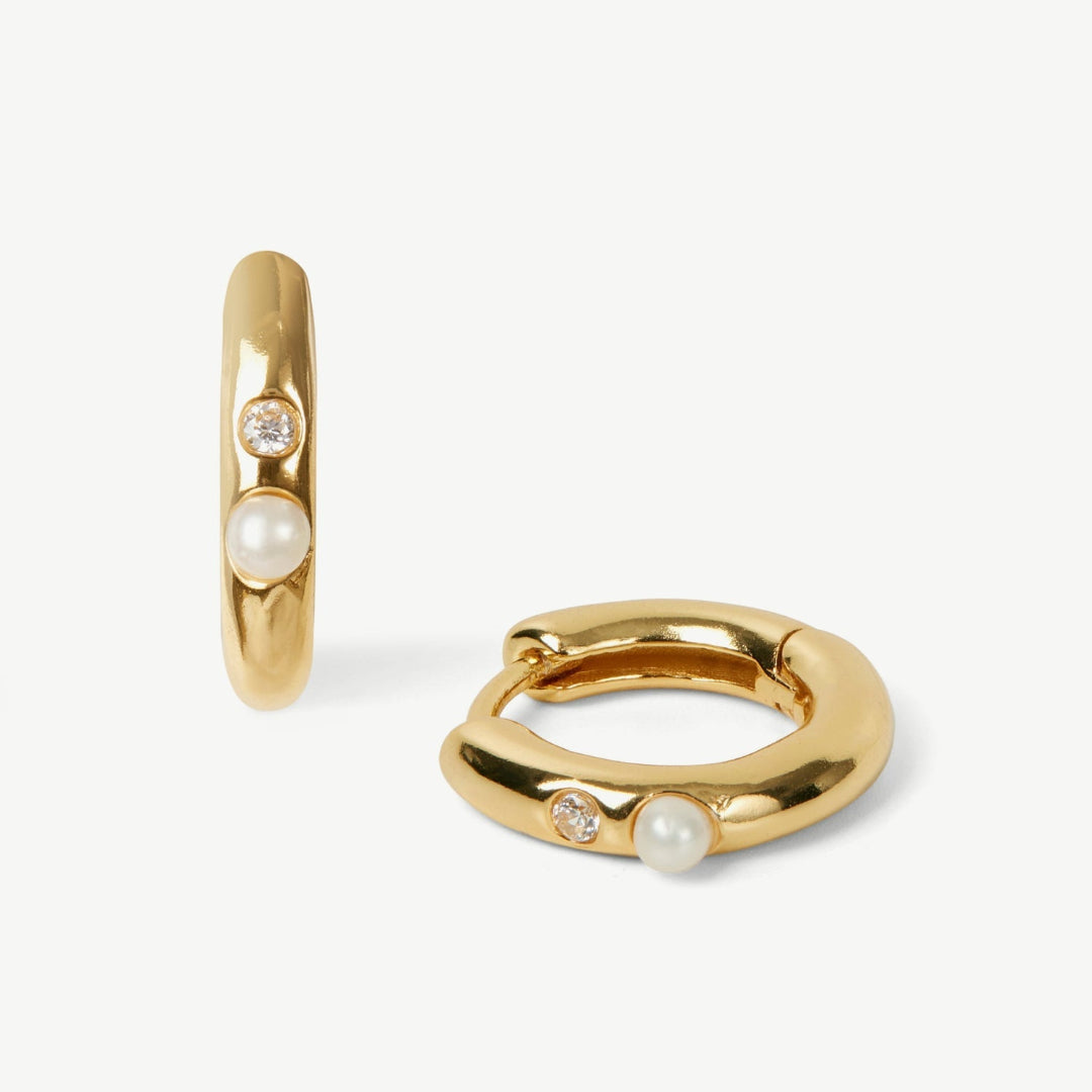 Gold hoop earrings with pearls on a white background