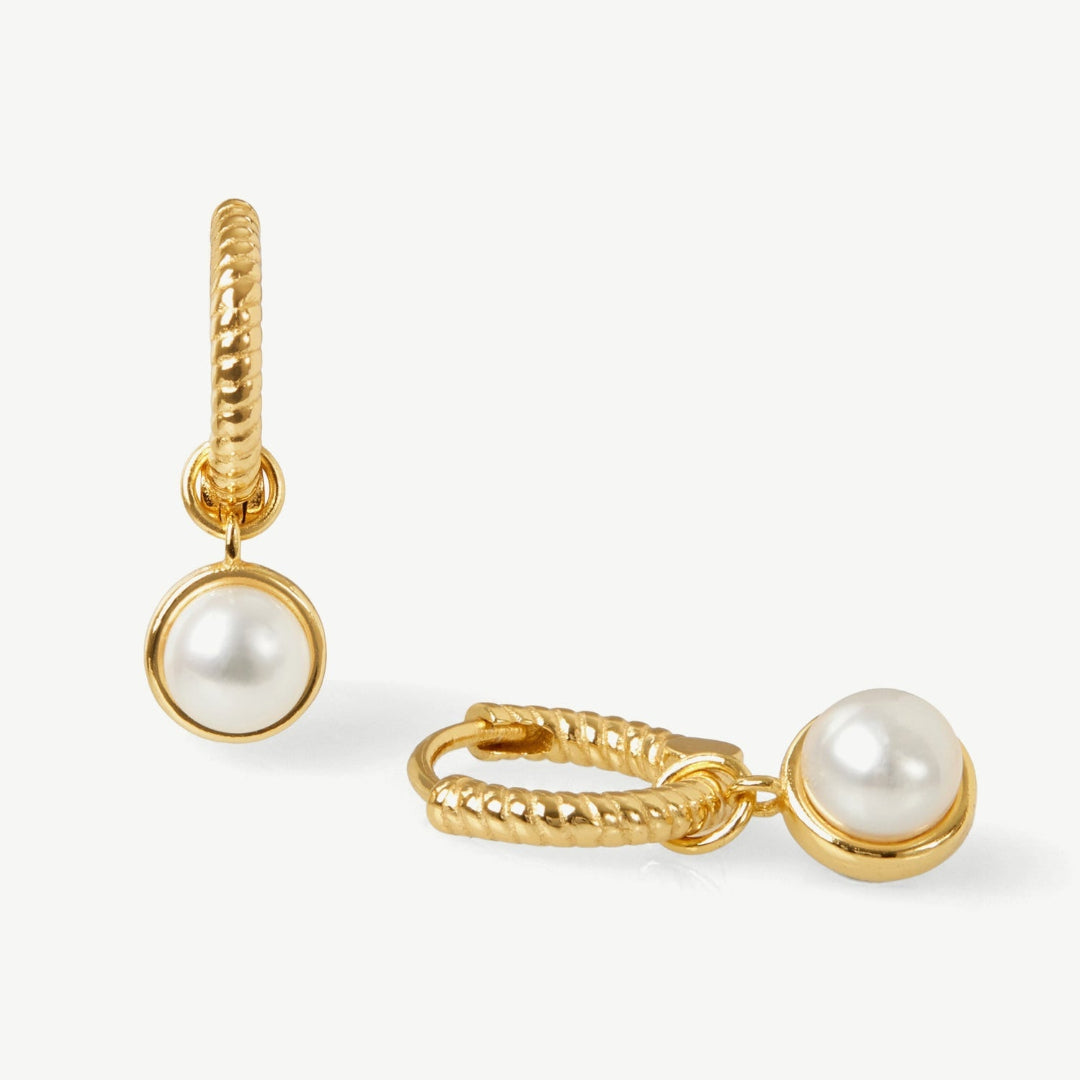 Gold hoop earrings with pearl drops on a white background