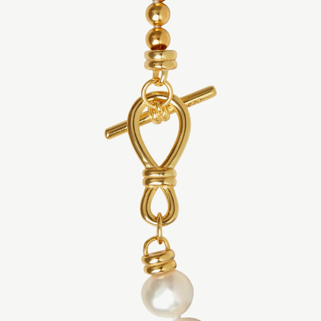 Gold necklace with a pearl pendant on a white background