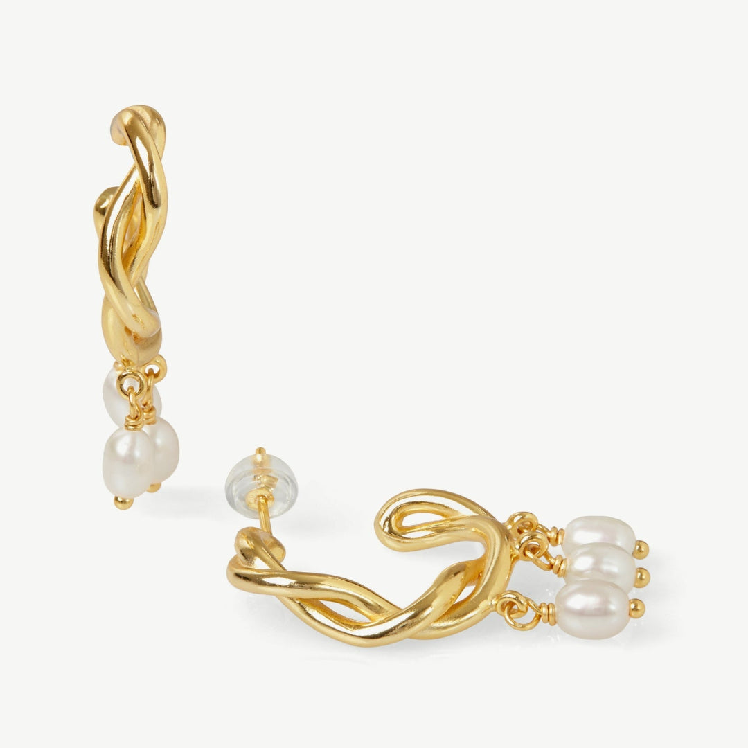 Gold hoop earrings with pearl drops on a white background