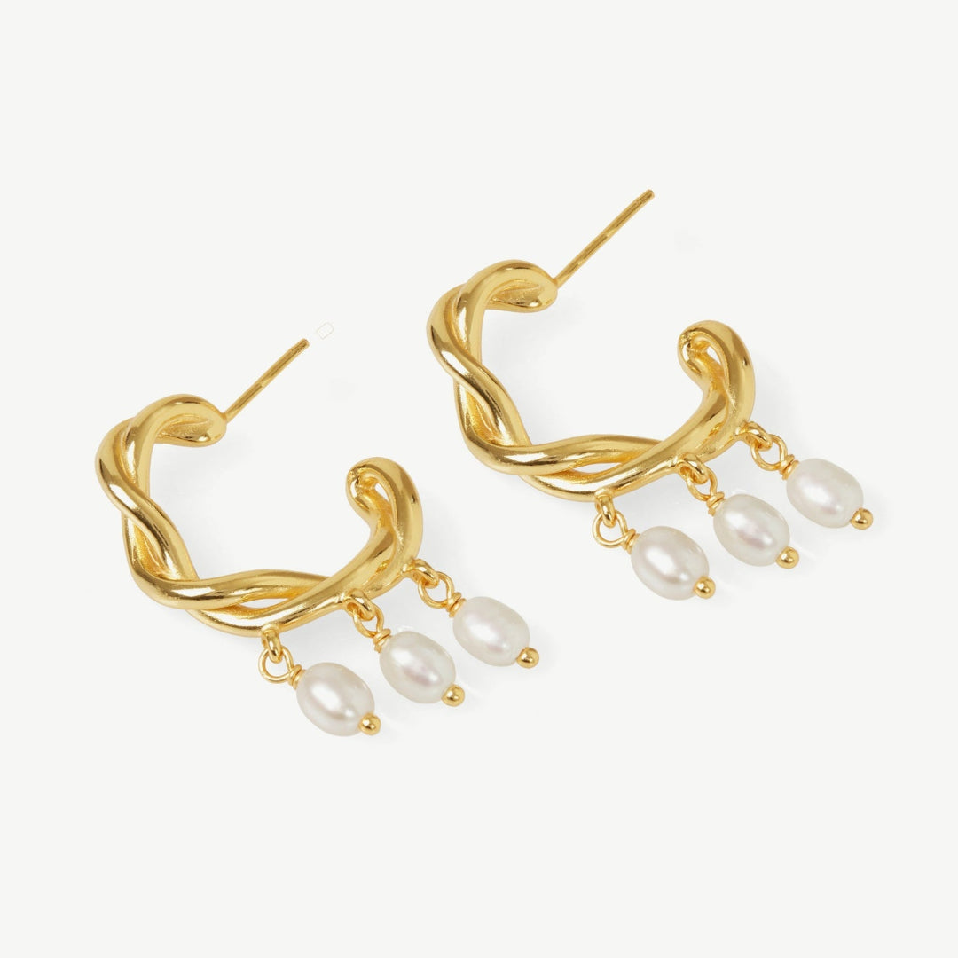 Gold hoop earrings with pearl drops on a white background