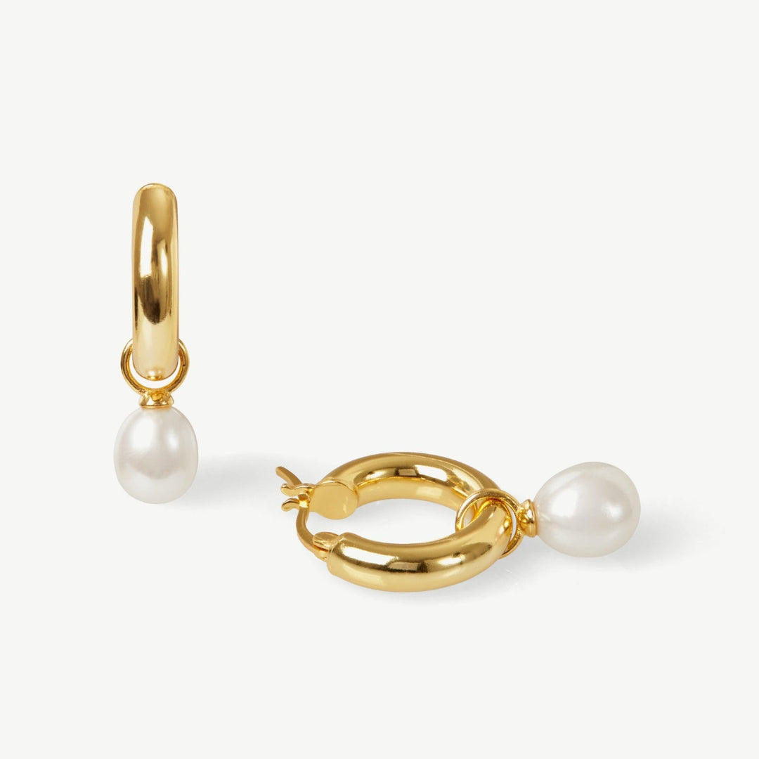 Gold hoop earrings with pearl drops on a white background