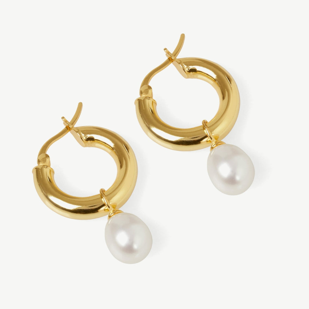 Gold hoop earrings with pearl drops on a white background