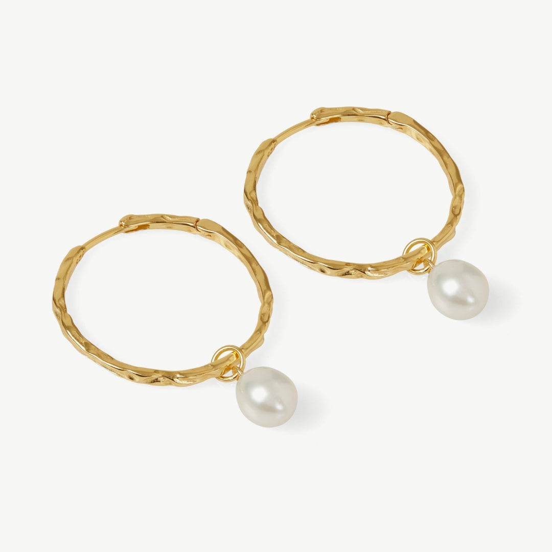 Gold hoop earrings with pearl drops on a white background