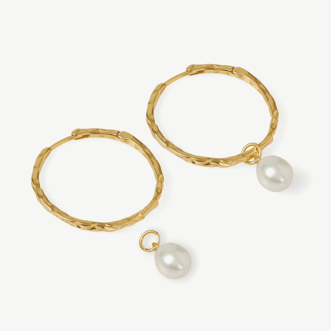 Gold hoop earrings with pearl drops on a white background