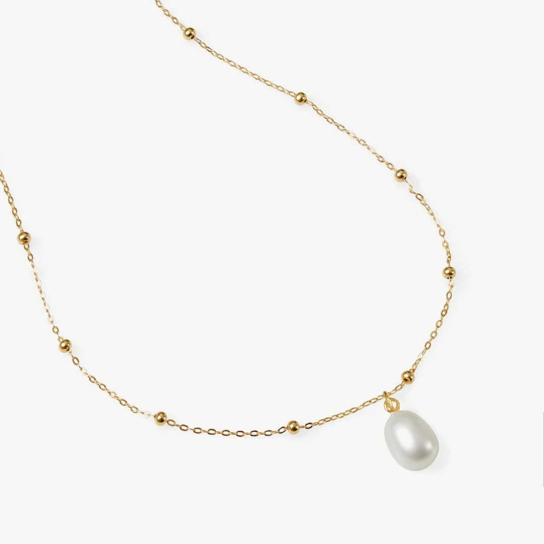 Gold necklace with a single pearl on a white background