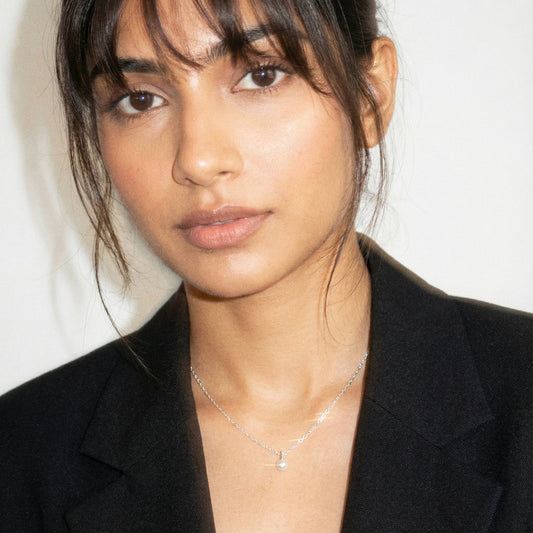 Woman wearing a black blazer and silver necklace against a white background