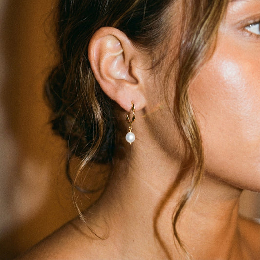 Close-up of a woman wearing a pearl earring with a blurred background