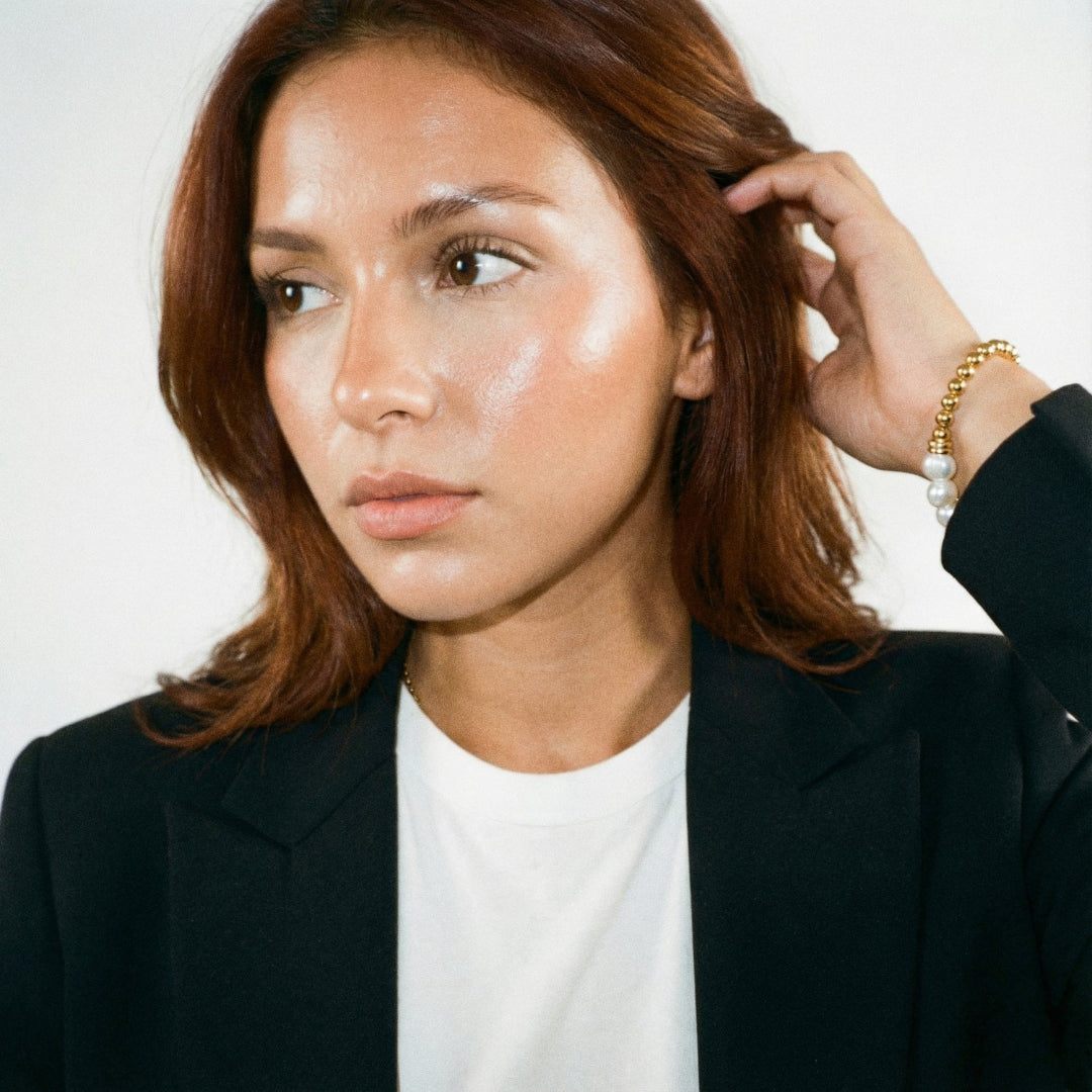 Woman adjusting her hair against a plain background