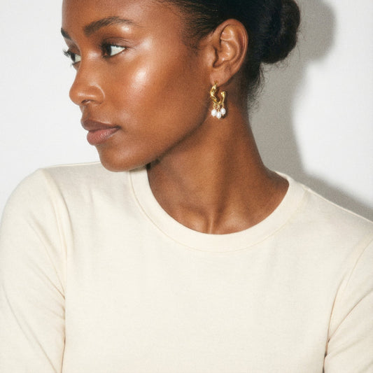 Woman wearing gold earrings with a neutral background